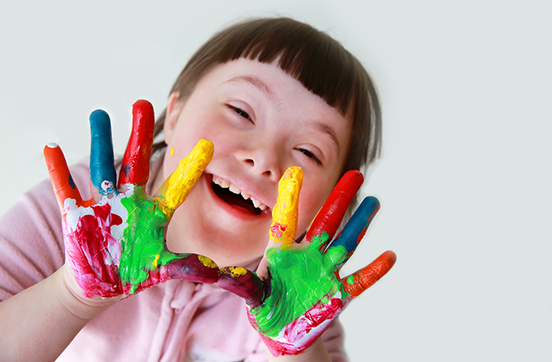 Child with special needs showing her hands that are painted rainbow