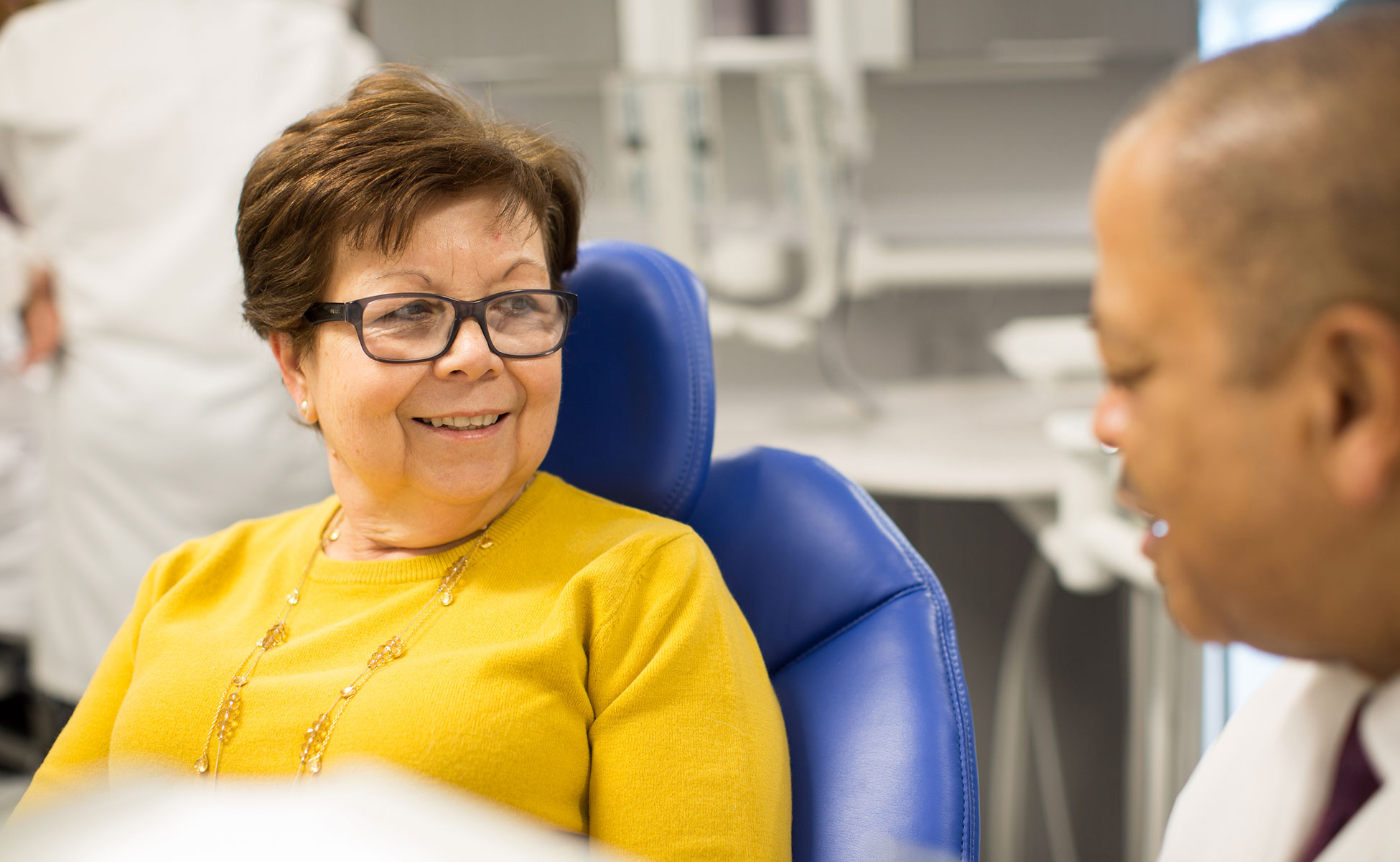 Female patient smiling and talking with dentist while sitting at appointment