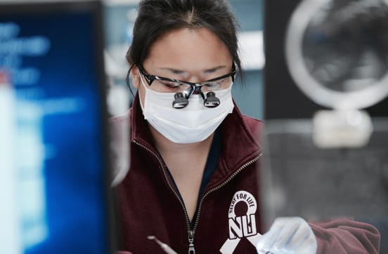 TCDM student using magnifying glasses in lab