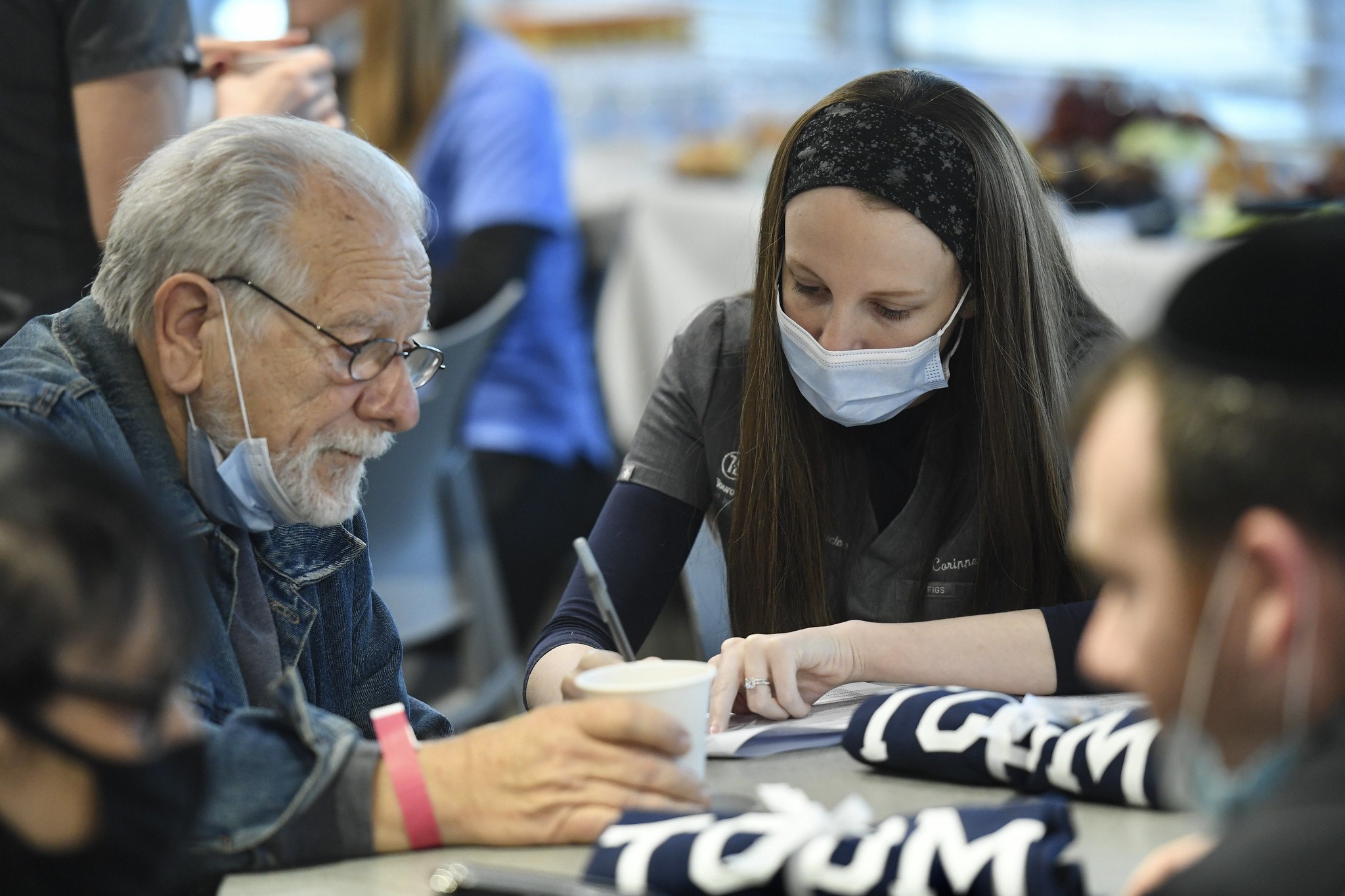 A student from TCDM helps an elderly veteran fill out paperwork. 