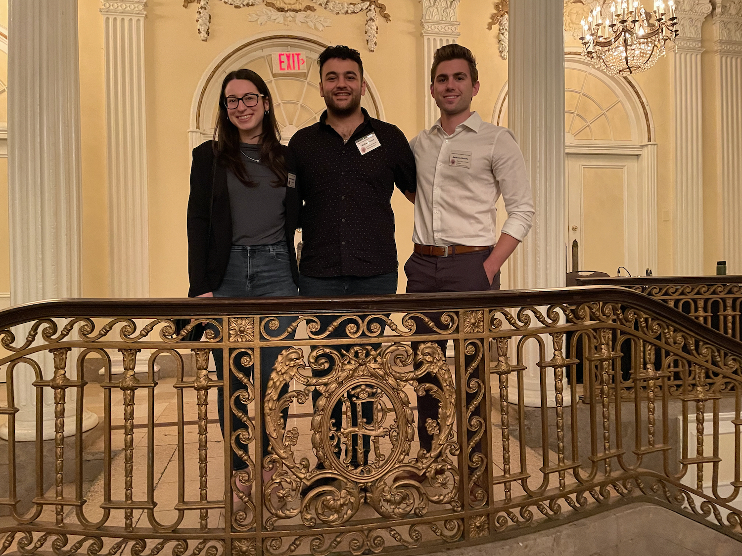 Three Touro College of Dental Medicine students and research poster presenters, stand on a balcony at the 27th Hinman Student Research Symposium. Left to right, third-year dental students Rachel Sebastien and Mullar Zakher, and fourth-year dental student Antony Muzika.