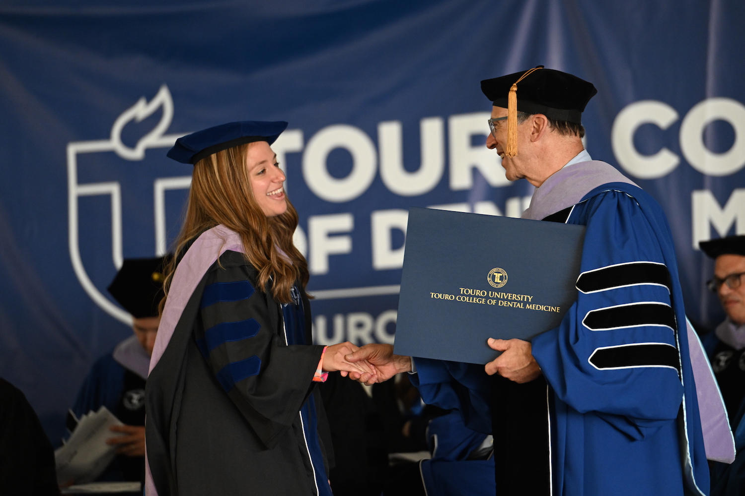 A Touro College of Dental Medicine student receives her diploma from the dean during the 2023 commencement. 