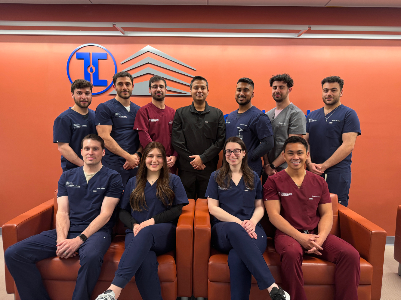 TCDM Research Society officers 2023-24, smiling and wearing dental scrubs in front of Touro logo