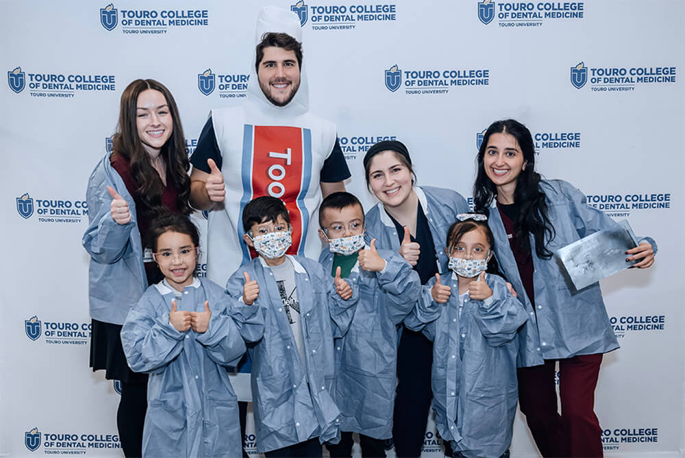 Touro dental students, one in a toothpaste costume, pose for photo with Long Island kindergartners